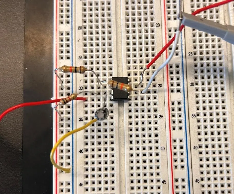 Close view of a breadboard with an op-amp chip, a few resistors and a capacitor wired up, with scope probe clips on the right