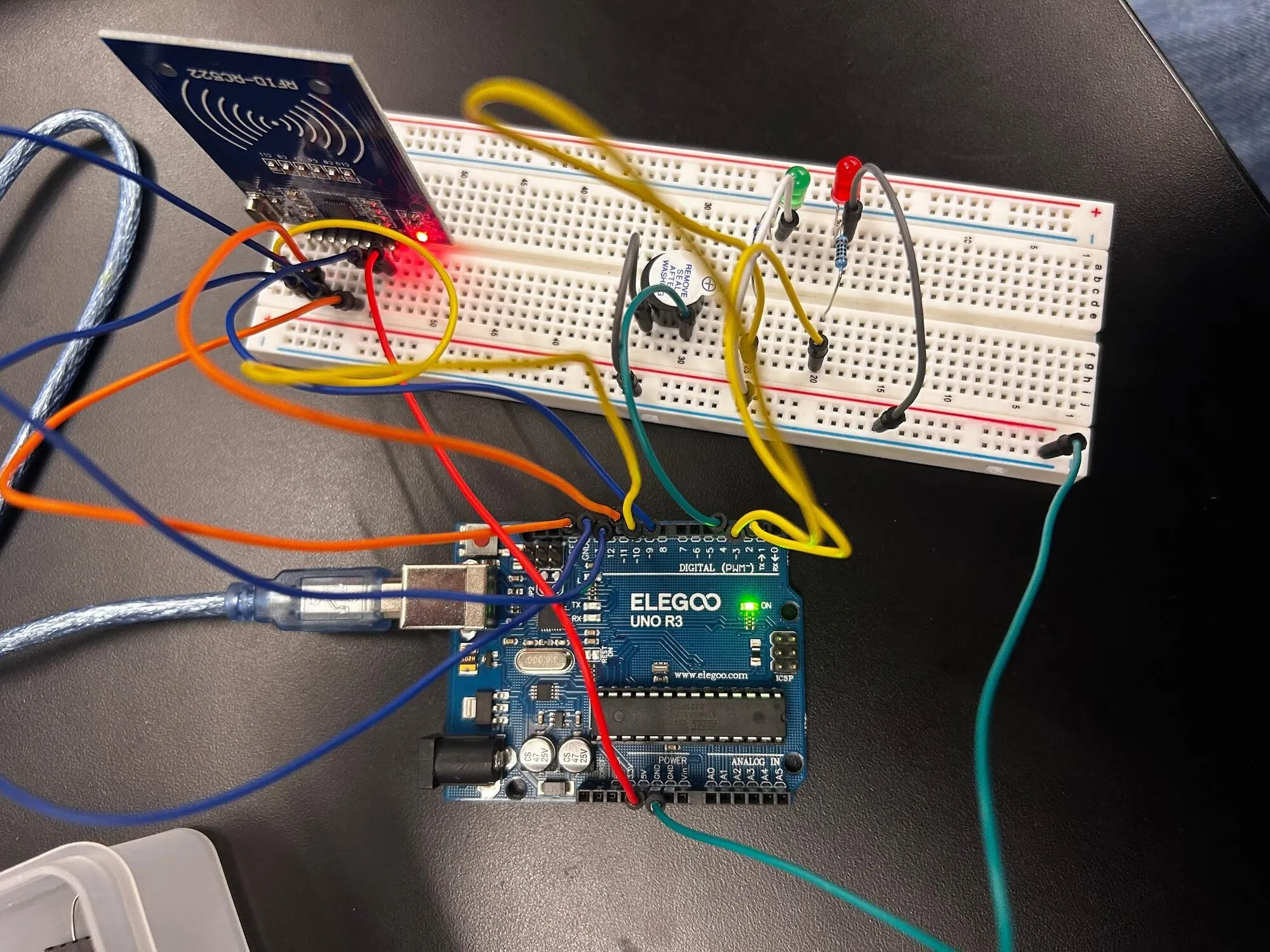 An Arduino Uno wired to an RC522 RFID module and a breadboard with a green LED, a red LED and a buzzer